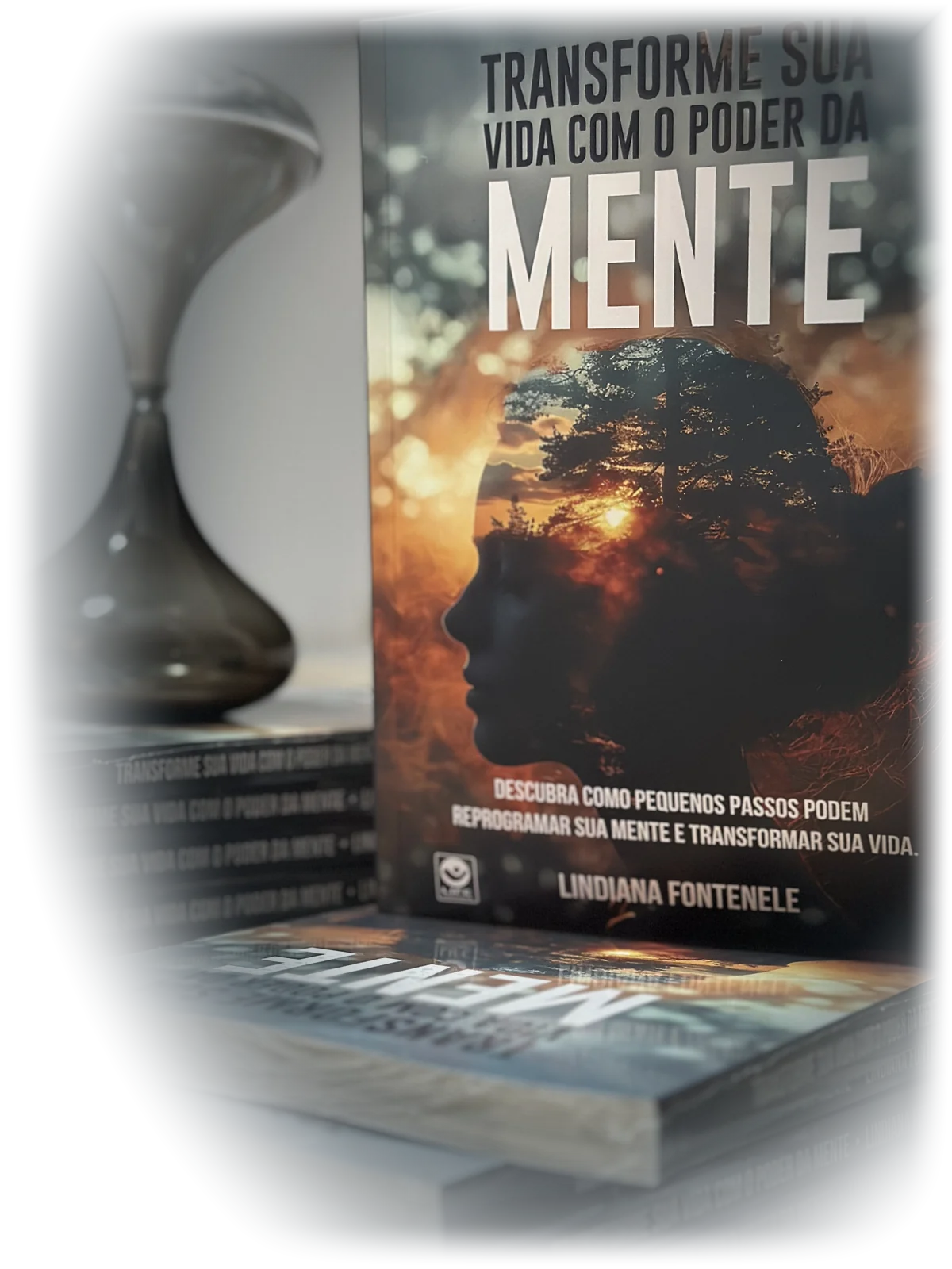 O livro Transforme sua Vida com o Poder da Mente ao lado de uma ampulheta